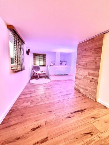 a living room with a wooden floor and a chair at Le Zen - Sauna - Balnéo - Sparoom Sarreguemines in Sarreguemines
