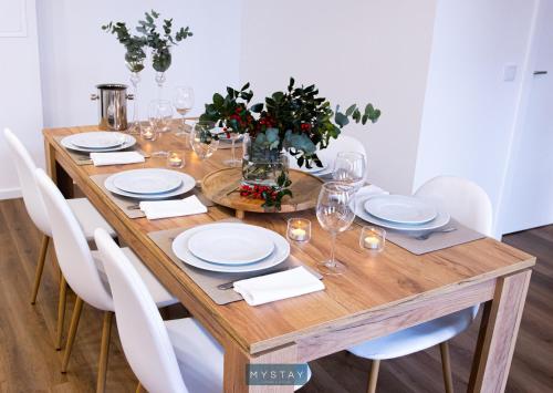 a wooden table with white plates and glasses on it at MyStay - D Maria Apartments in Vila Nova de Famalicão