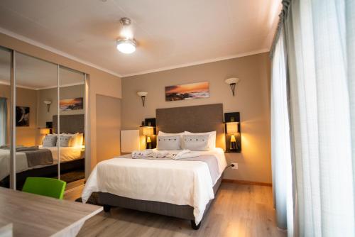 une chambre d'hôtel avec un lit et un miroir dans l'établissement Meadowbrook Guesthouse, à Pretoria