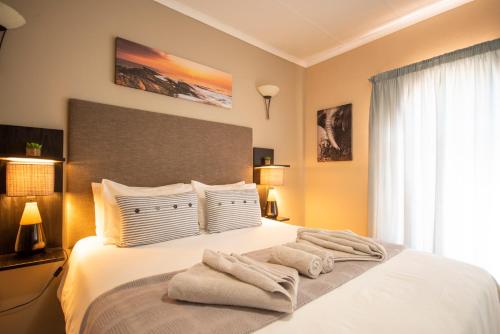 Un dormitorio con una cama blanca con toallas. en Meadowbrook Guesthouse, en Pretoria