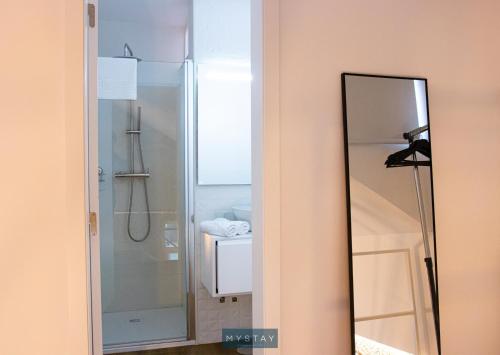 uma casa de banho com um chuveiro e um espelho. em MyStay - D Maria Apartments em Vila Nova de Famalicão