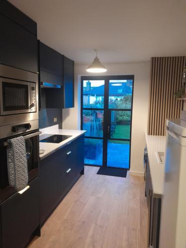 a kitchen with black cabinets and a door to a patio at WELCOMEHOUSE close to east beach, shops, restaurants and RAF base in Lossiemouth