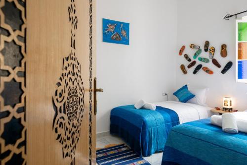 een slaapkamer met 2 bedden en een open deur met een kier bij RIAD AMR in Tanger