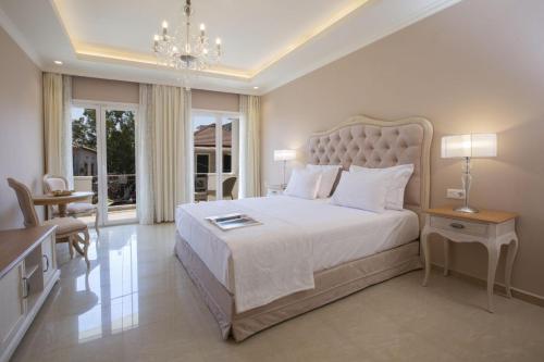 una camera con un grande letto e un lampadario a braccio di VK Luxury Suites Nidri Lefkada - Adults Only a Nydri