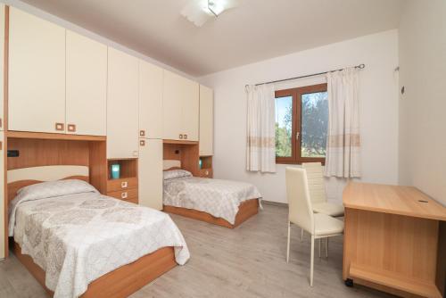 Appartamento Bellavista في Telti: غرفة نوم بسريرين ومكتب وطاولة