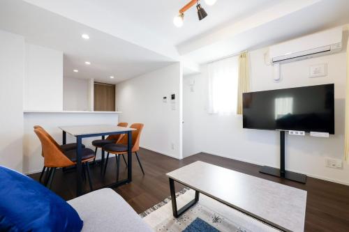 a living room with a tv and a table with chairs at MAT SHIBUYAHONMACHI in Tokyo