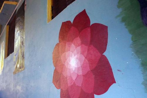 a painting of a red flower on a wall at Clan Boho in Rishīkesh