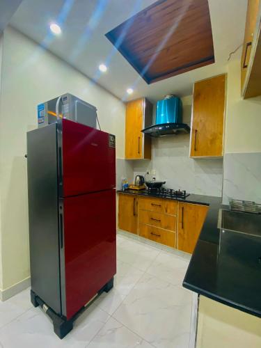 ラホールにあるLuxury Apartment in Bahria Town, Lahoreのキッチン(赤い冷蔵庫、木製キャビネット付)