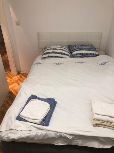białe łóżko z ręcznikami i poduszkami w obiekcie Empire Apartments w mieście Skopje