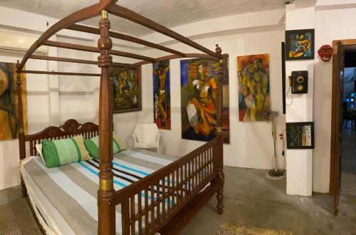 a bedroom with a canopy bed with paintings on the walls at Segar Art Gallery in Ja-Ela