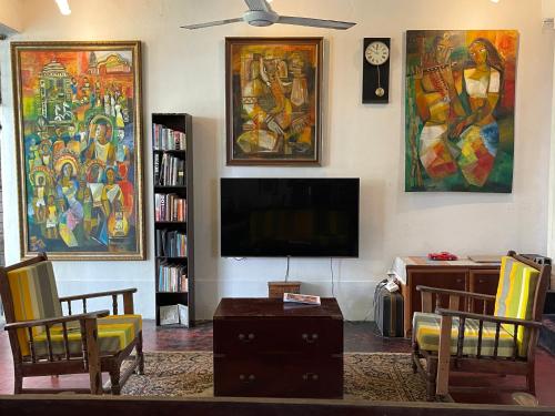 a living room with a tv and paintings on the wall at Segar Art Gallery in Ja-Ela