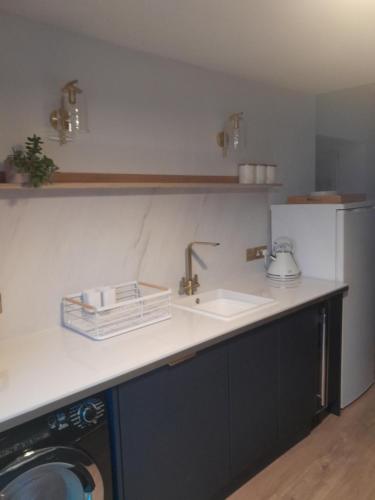 a kitchen counter with a sink and a refrigerator at WELCOMEHOUSE close to east beach, shops, restaurants and RAF base in Lossiemouth