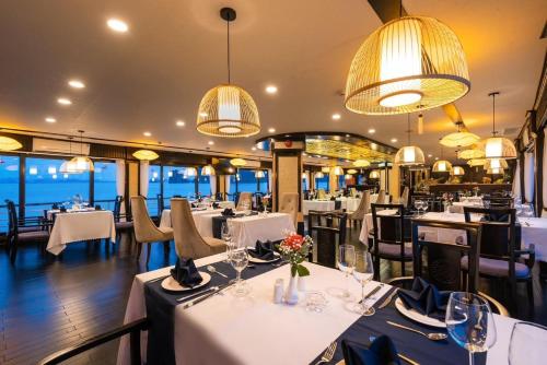 restauracja z białymi stołami, krzesłami i światłami w obiekcie Aquamarine Premium Cruise w Ha Long
