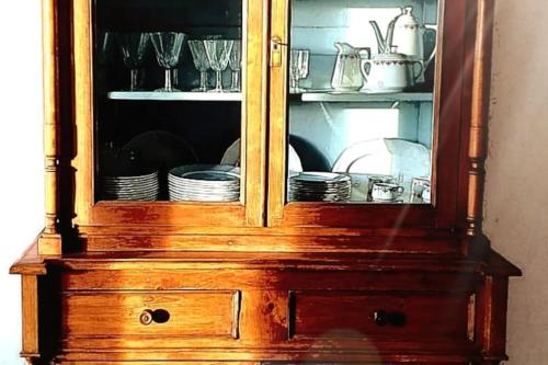 einem Holzschrank mit Tellern und Geschirr in der Unterkunft La casa dei nonni tra Crete Senesi e Val D'Orcia in San Giovanni dʼAsso