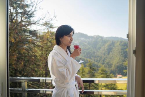 a woman in a white robe holding a glass of wine at The Namah Retreat By PerfectStayz in Shimla