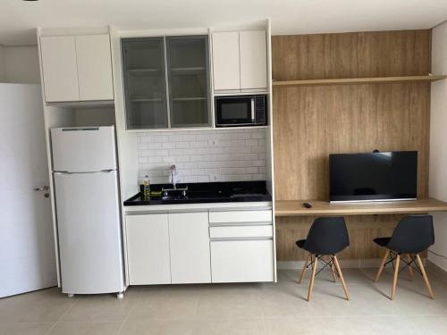 a kitchen with white cabinets and a white refrigerator at Studio metrô Belém 2 in Sao Paulo