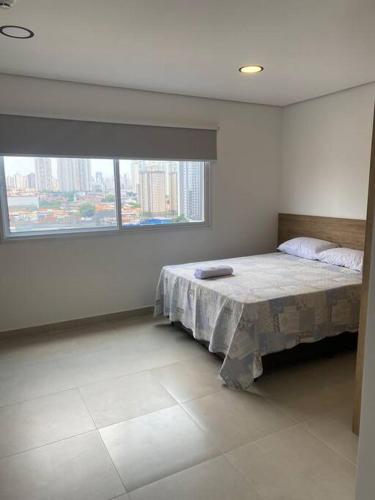 a bedroom with a bed and a large window at Studio metrô Belém 2 in Sao Paulo
