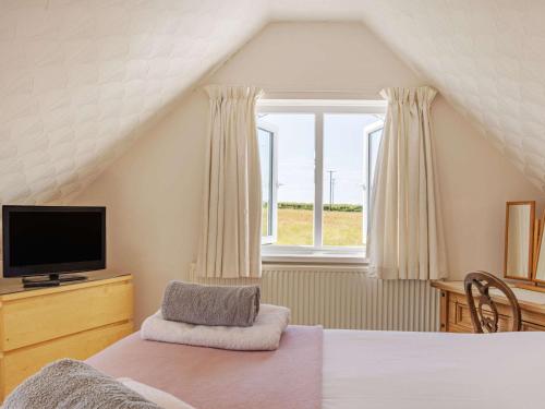 a bedroom with a bed and a tv and a window at 4 Bed in Broad Haven 88331 in Saint Ishmaels