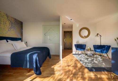 a bedroom with a bed and two blue chairs at Falkensteiner Hotel Adriana - Adults Only in Zadar