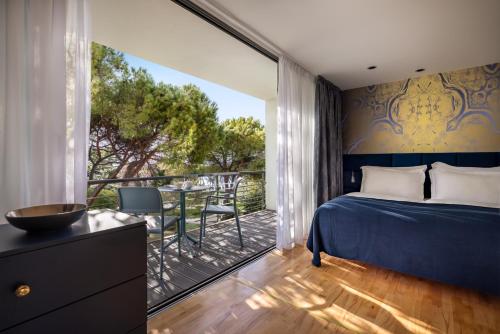 a bedroom with a bed and a balcony with a table at Falkensteiner Hotel Adriana - Adults Only in Zadar