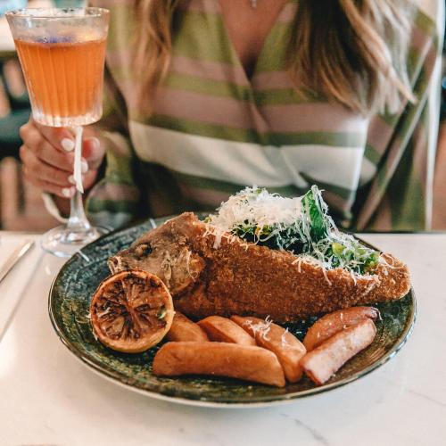 a plate of food on a table with a glass of wine at The Chow Kit - an Ormond Hotel in Kuala Lumpur