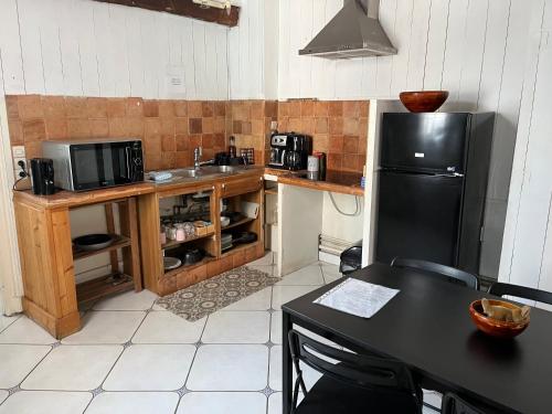 a kitchen with a black refrigerator and a table at les Pastoureaux in Orléans