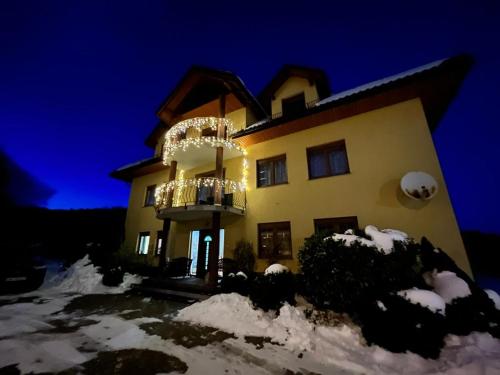 a house with a balcony in the snow at night at Willa Sielanka in Karpacz