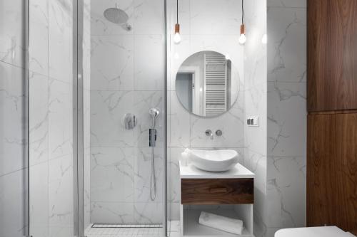 a bathroom with a shower with a sink and a mirror at Elite Apartments Luna Spa&Welness in Gdańsk