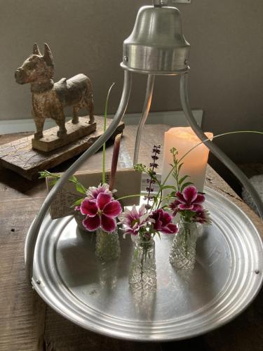 a table with a lamp and flowers in glass vases at Romantikurlaub im Zirkuswagen in Hümmel