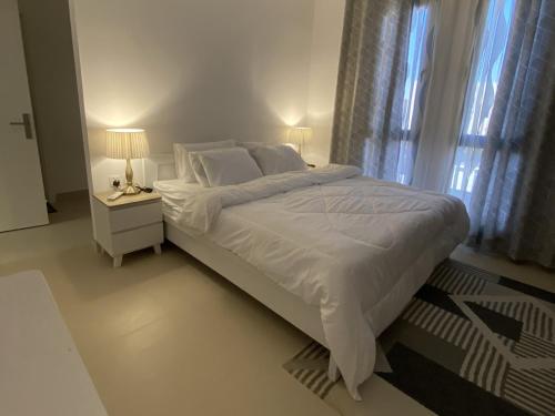 a white bedroom with a large bed and a window at Sidrah House in Riyadh