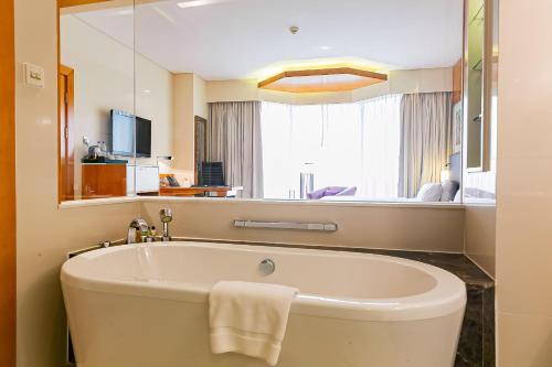 a bath tub in a bathroom with a large mirror at Lagos Continental Hotel in Lagos