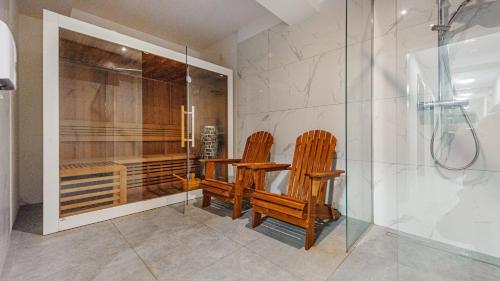two wooden chairs in a bathroom with a shower at Apartamenty Sun & Snow WISUS in Świnoujście