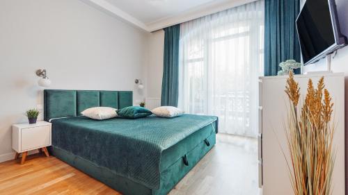 a bedroom with a green bed and a large window at Apartamenty Sun & Snow WISUS in Świnoujście