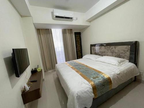 ein Schlafzimmer mit einem Bett und einem TV in der Unterkunft Cozy Studio Unit in Casaren in Batam Center