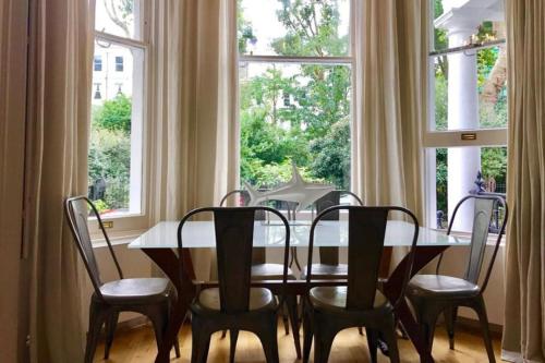 a dining room table and chairs in front of a window at Stunning 2 bed/2bath flat in heart of Kensington in London