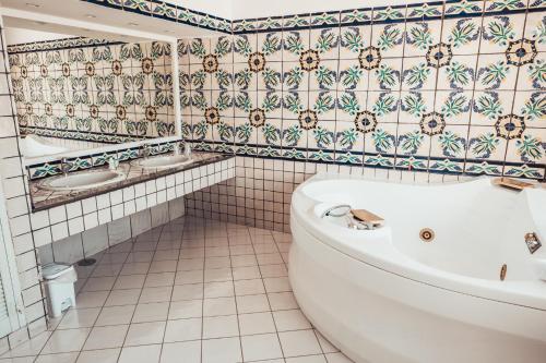 a bathroom with a tub and a tiled wall at Hotel Oriente in Vico Equense