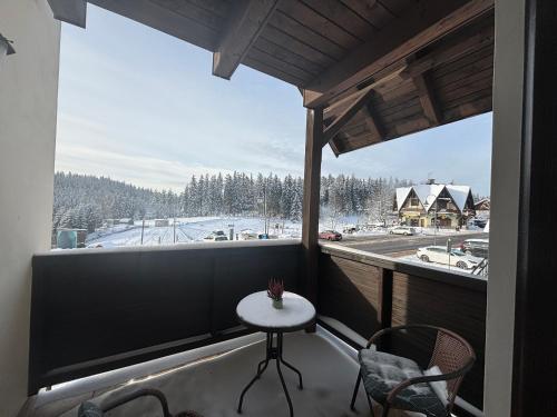 a balcony with a table and chairs and a large window at Penzion Verde Rosa in Harrachov
