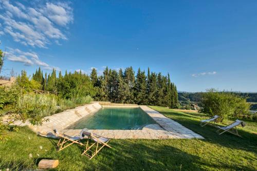 a swimming pool with two lawn chairs in a yard at Tenuta di Megognano in Poggibonsi