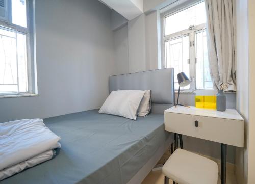 a bedroom with a bed and a desk and windows at Student Accommodation - 290 Hennessy Road in Hong Kong