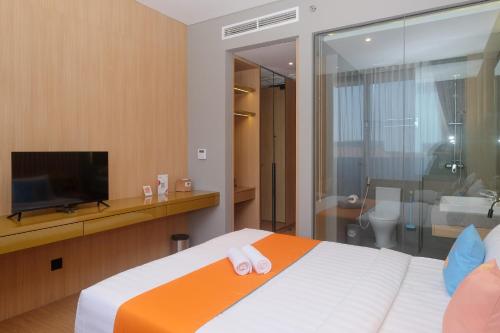 a bedroom with a bed with a television and a bathroom at Sans Hotel RG Living Jogja by RedDoorz in Demangan
