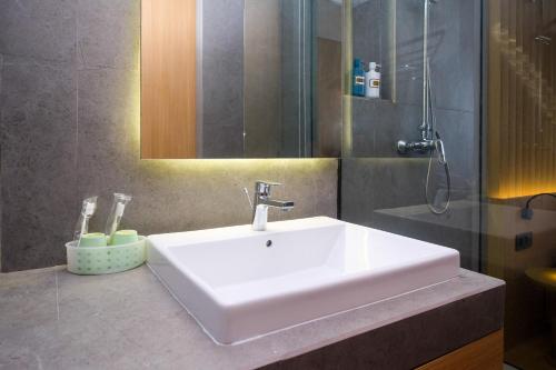 a bathroom with a white sink and a shower at Sans Hotel RG Living Jogja by RedDoorz in Demangan