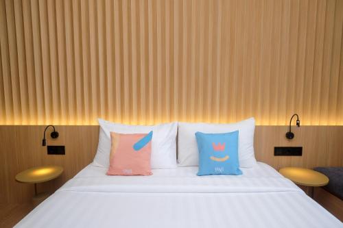a bed with three pillows on top of it at Sans Hotel RG Living Jogja by RedDoorz in Demangan