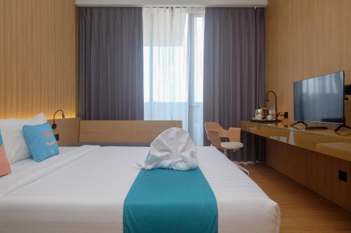 a hotel room with a bed and a television at Sans Hotel RG Living Jogja by RedDoorz in Demangan