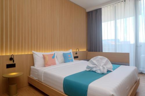 a hotel room with a bed with a towel on it at Sans Hotel RG Living Jogja by RedDoorz in Demangan