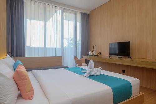 a bedroom with a bed with a stuffed animal on it at Sans Hotel RG Living Jogja by RedDoorz in Demangan