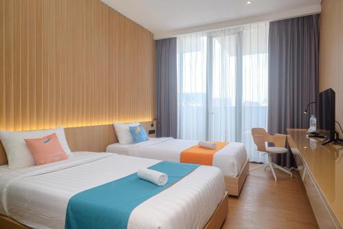 um quarto de hotel com duas camas e uma secretária em Sans Hotel RG Living Jogja by RedDoorz em Demangan