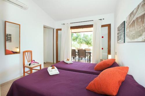 sypialnia z 2 łóżkami z purpurową pościelą i pomarańczowymi poduszkami w obiekcie Villa Figueral by Villa Plus w Alcudii