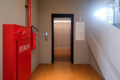 a hallway with an elevator and a red fire hydrant at Sans Hotel RG Living Jogja by RedDoorz in Demangan