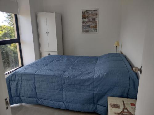a bedroom with a bed with a blue comforter at BAHIA SAN FRANCISCO, casa Horneros, 3 Dormitorios, Uruguay in Piriápolis