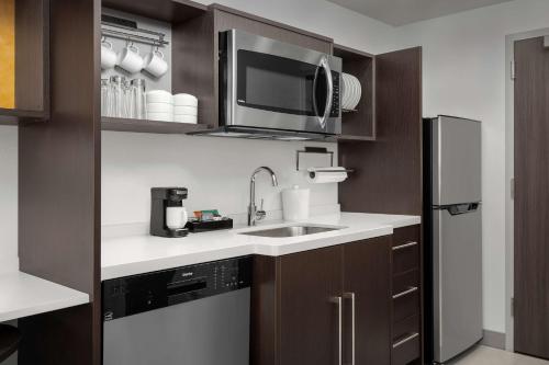 a kitchen with a sink and a microwave at Home2 Suites Orlando Southeast Nona in Orlando